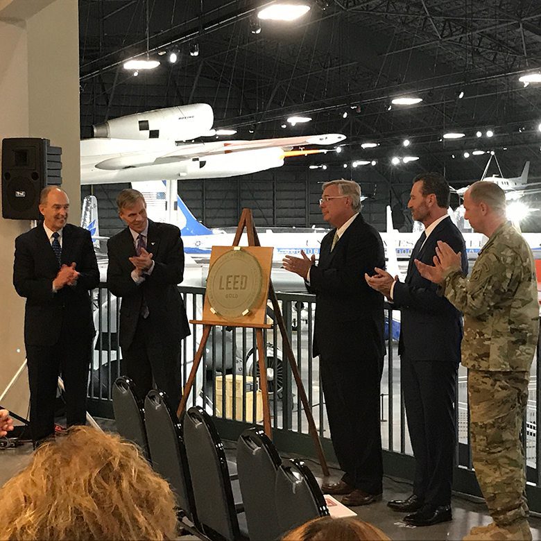 Group of men clapping with gold LEED award