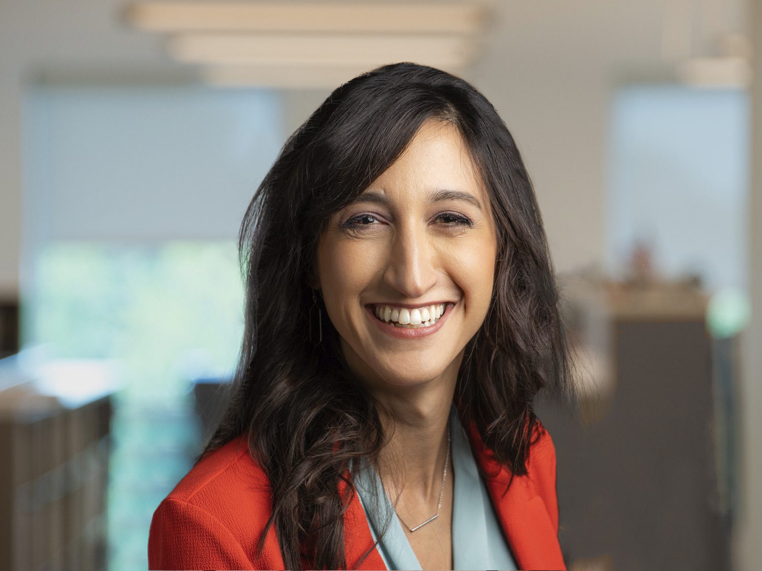 Headshot of dark haired woman with red jacket