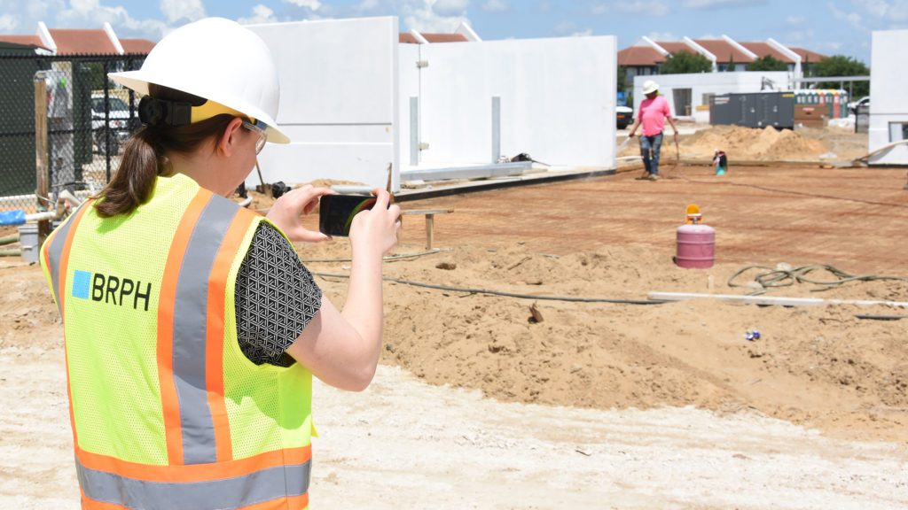 female foreman on construction site holding a laptop