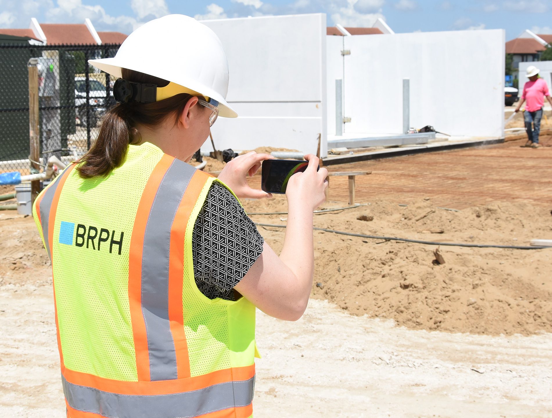 Employee in yellow vest taking pics of dirt brown lot