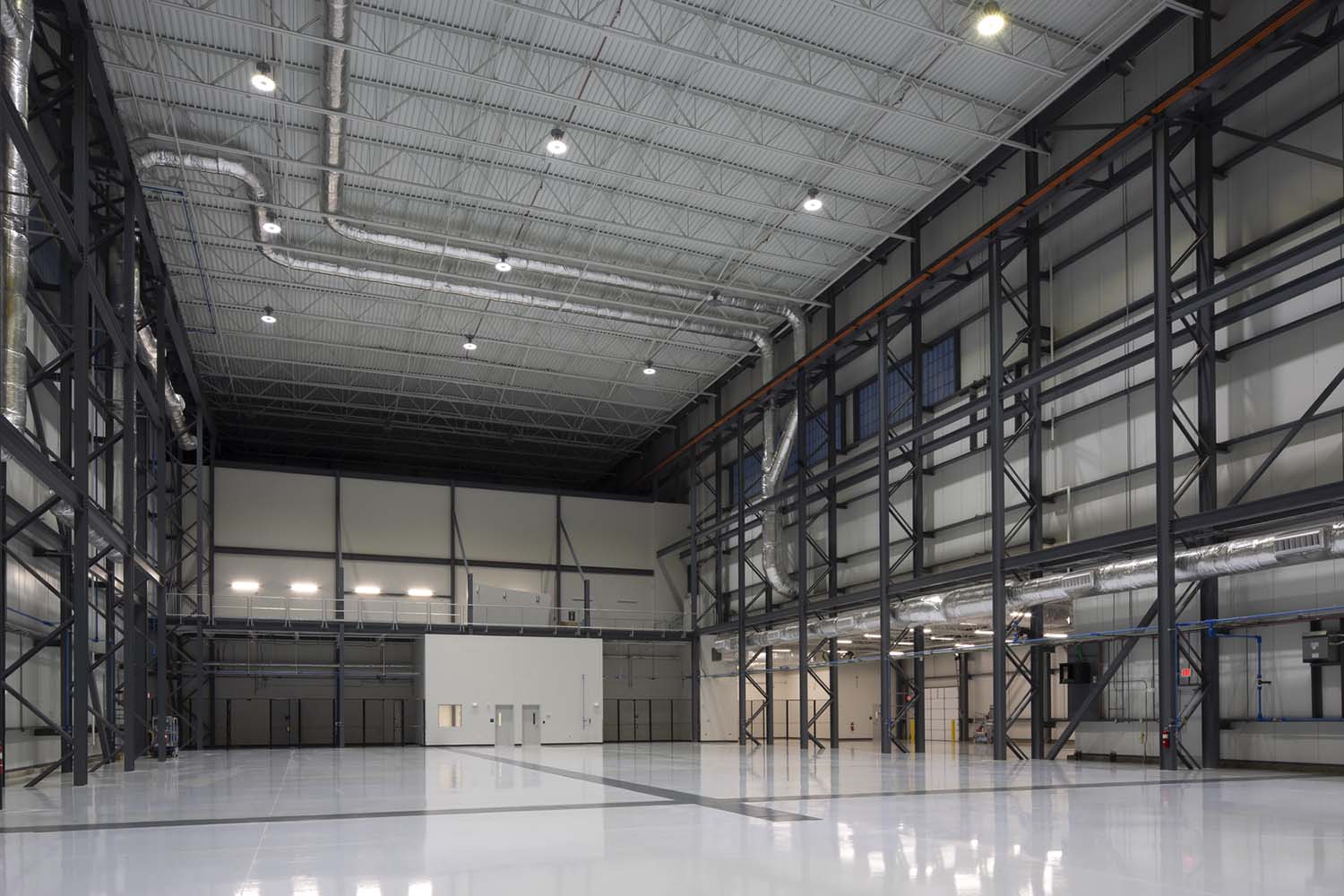 Large warehouse with white floor and metal beams on wall