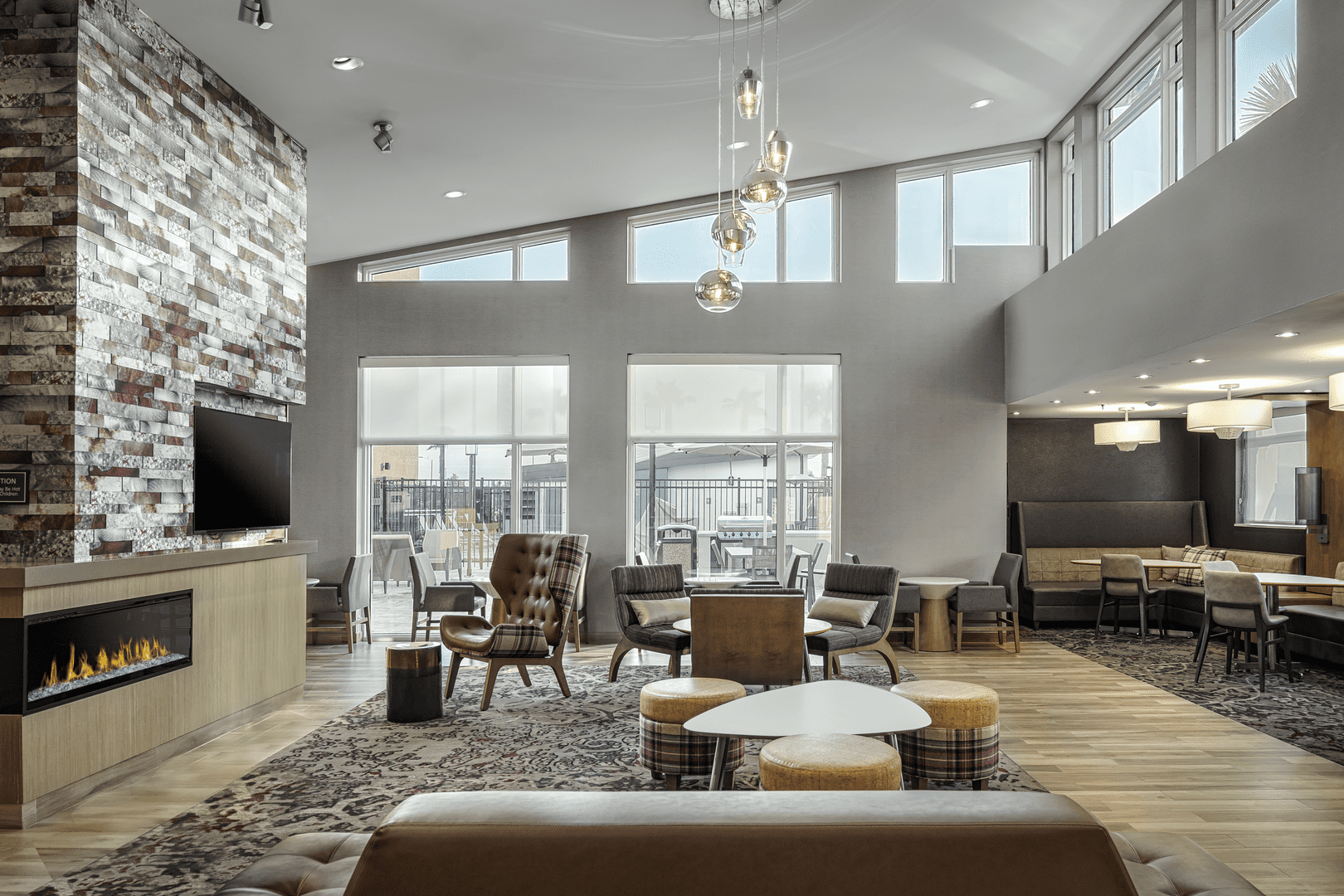 Hotel lobby with brown chairs/couches and brick fireplace and gray walls