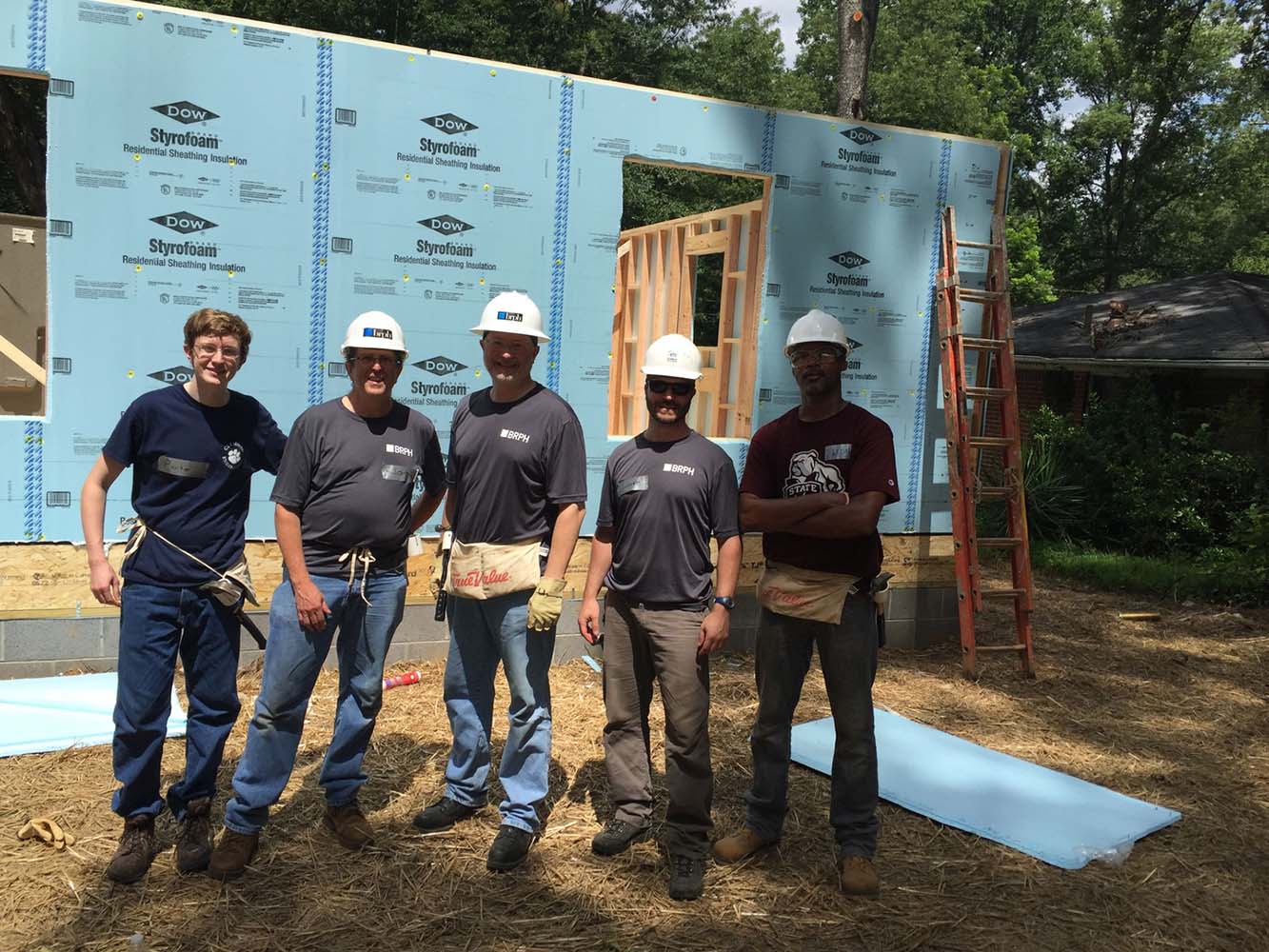 5 men posing in front of housing construction