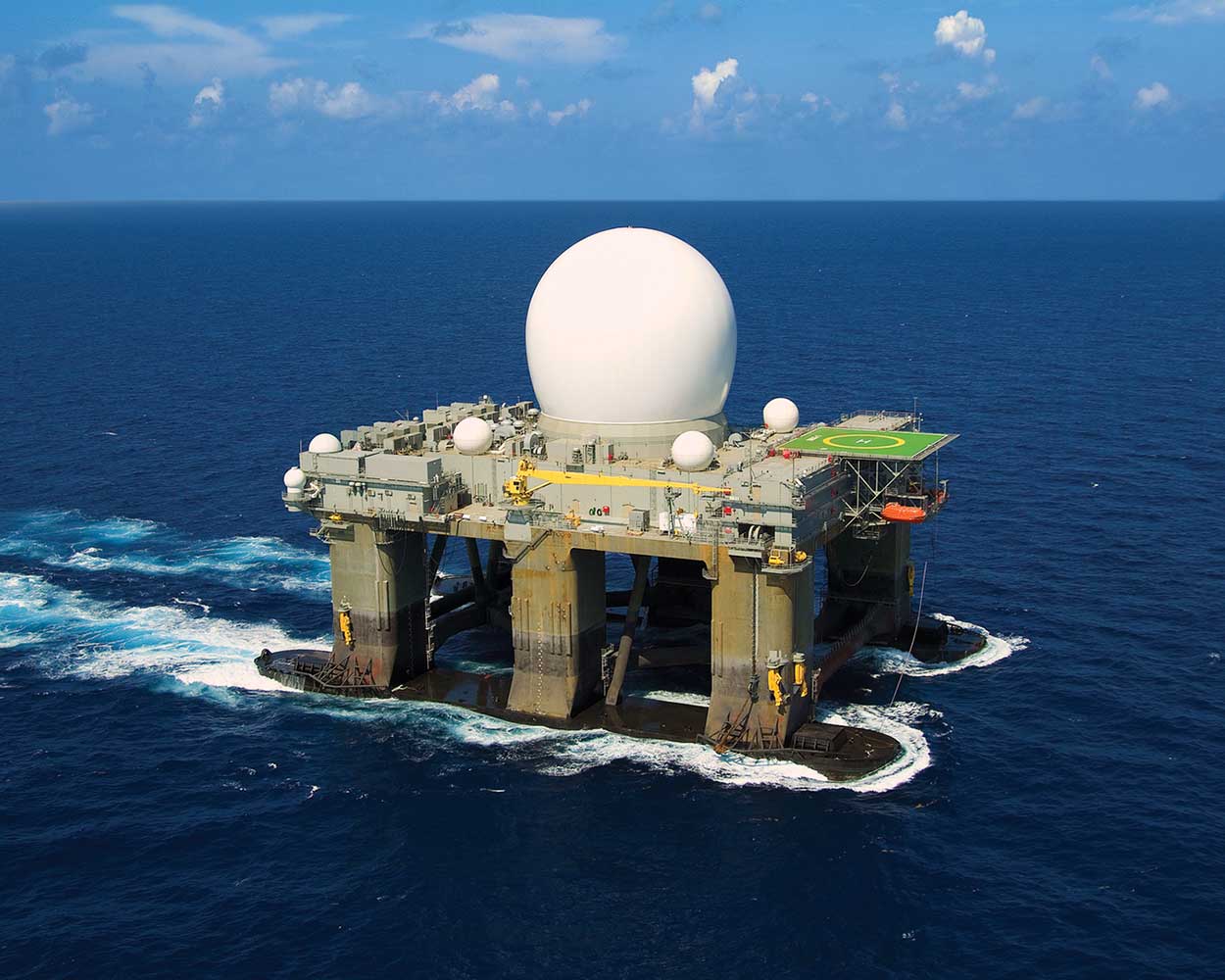 Large white antenna globe on dock station in ocean
