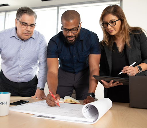 3 BRPH team members looking at a blueprint