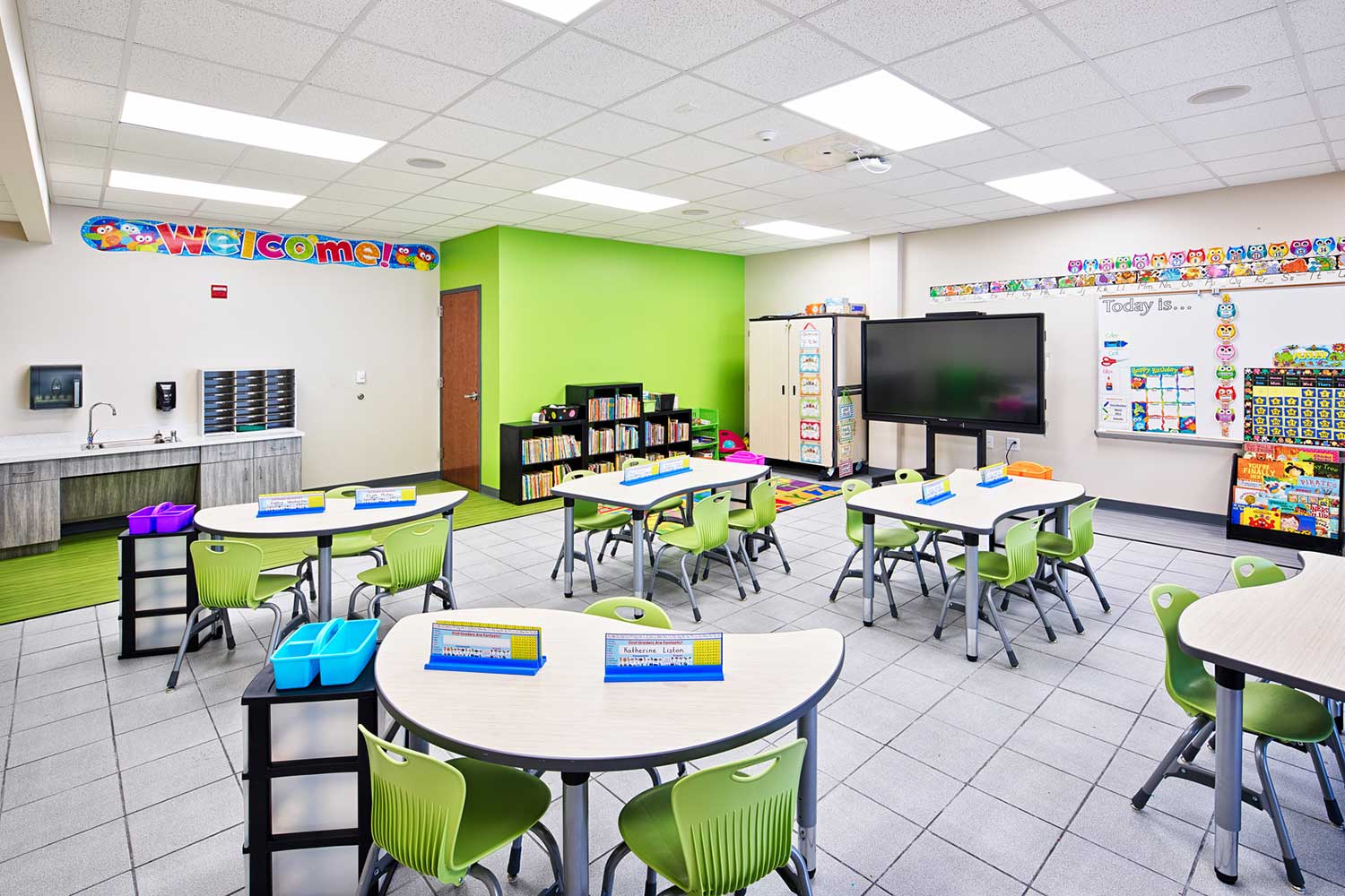 School classroom with green chairs and white tables