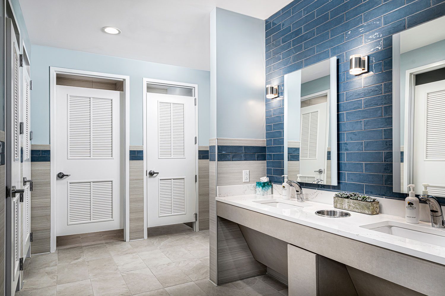 Light Blue and gray bathroom with blue brink wall behind sinks