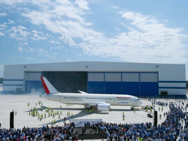 Commercial airliner parked in front of hangar with lots of people standing around it for the grand opening of the Boeing 787 Dreamliner Final Assembly Building