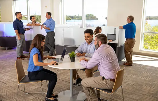 Group of 3 coworkers talking at a small circular table