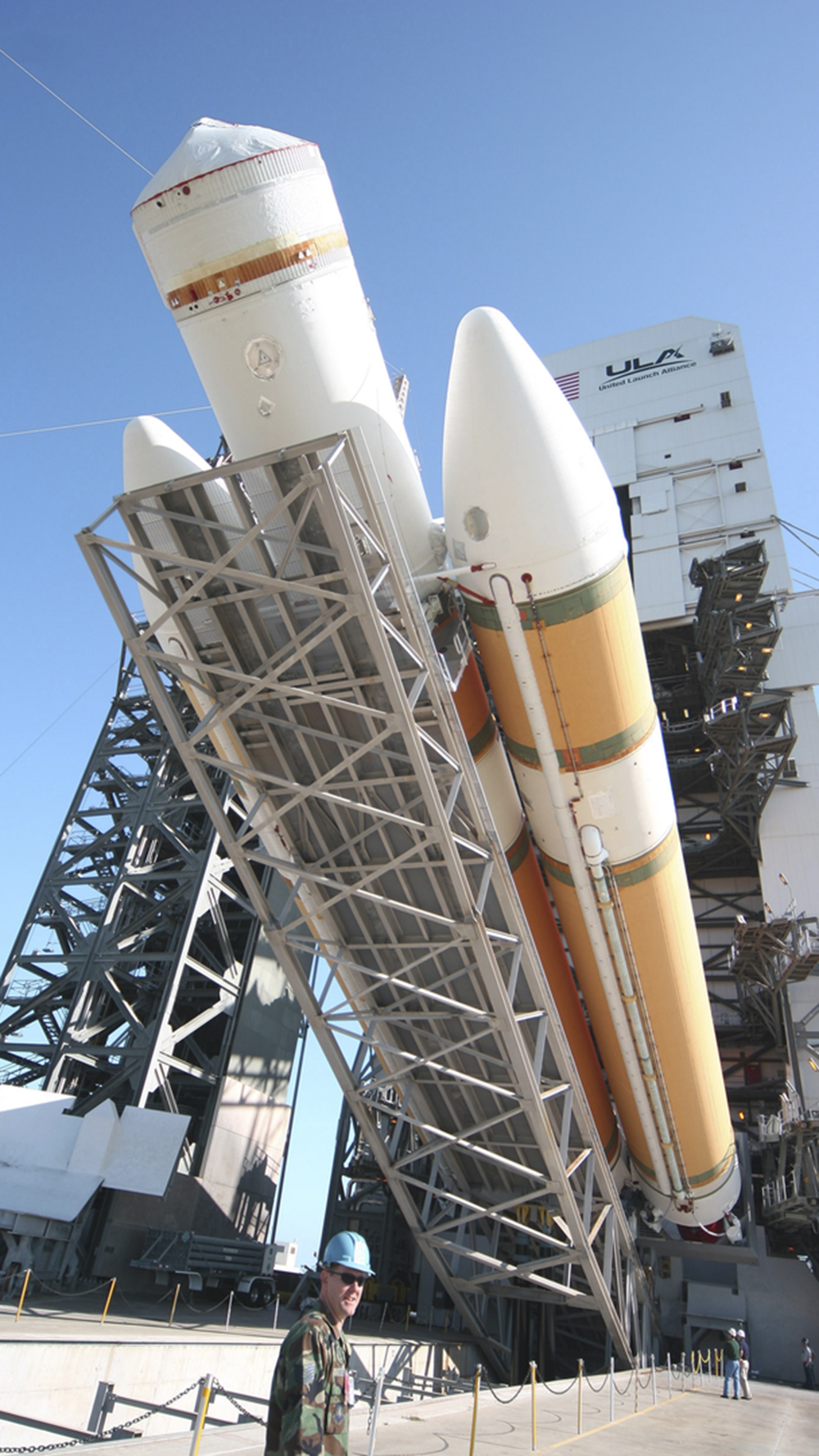 orange and white ULA rocket on raising white launch pad