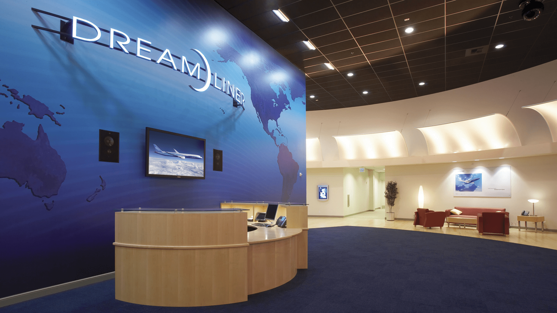 Blue wall displaying dark blue continents with tan reception desk and navy carpet