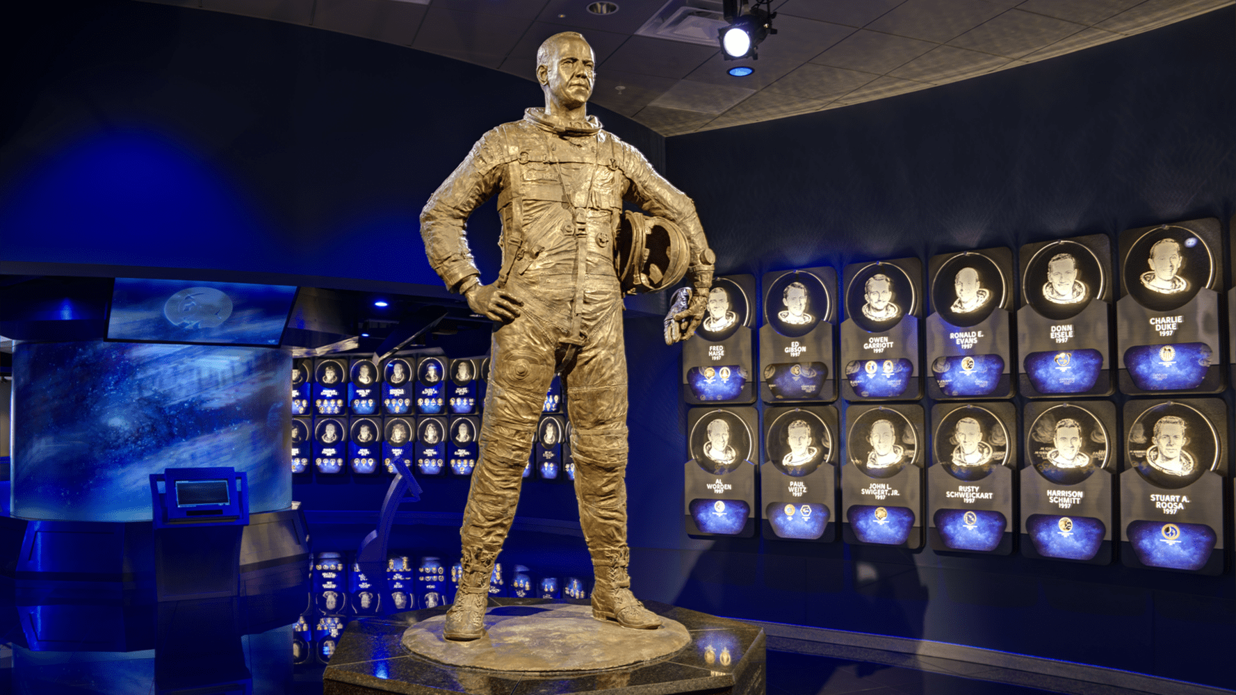 Gold astronaut statue in purple room with black/white pictures on the wall