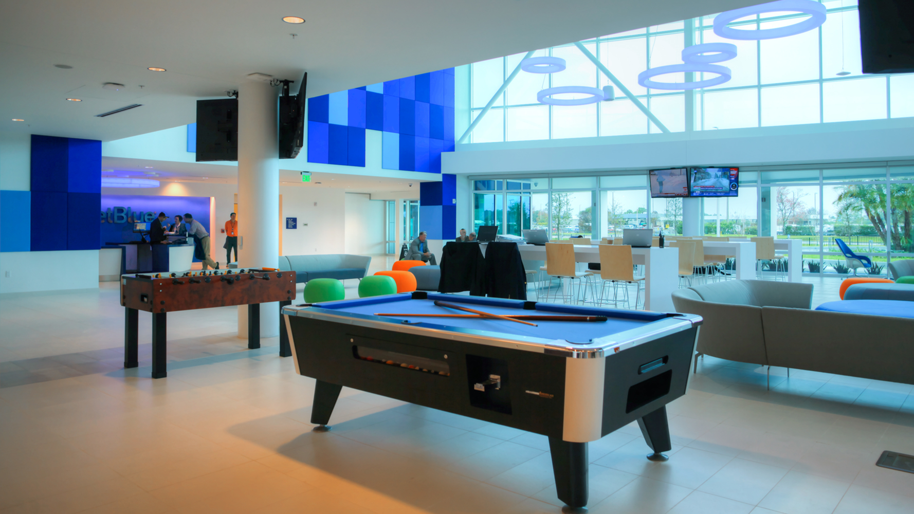 Black and blue pool table with brown table soccer game and gray sofas with tan floors