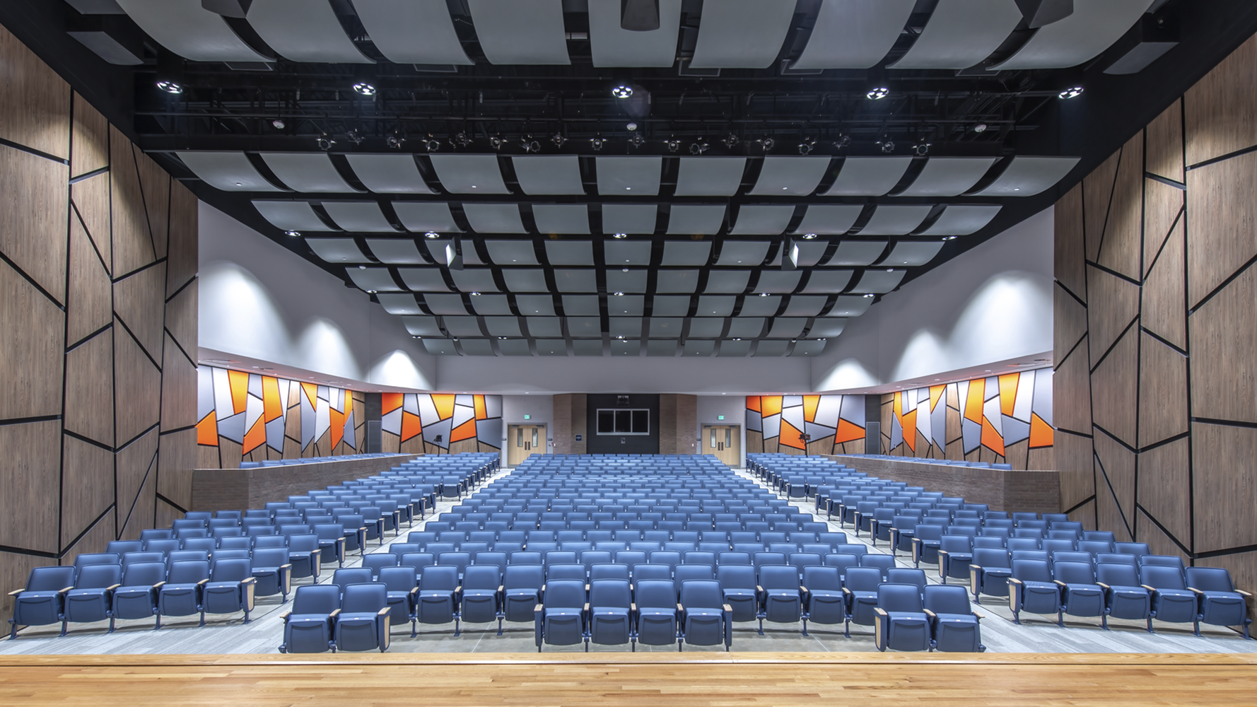Auditorium with blue chairs, brown and orange walls, gray ceiling
