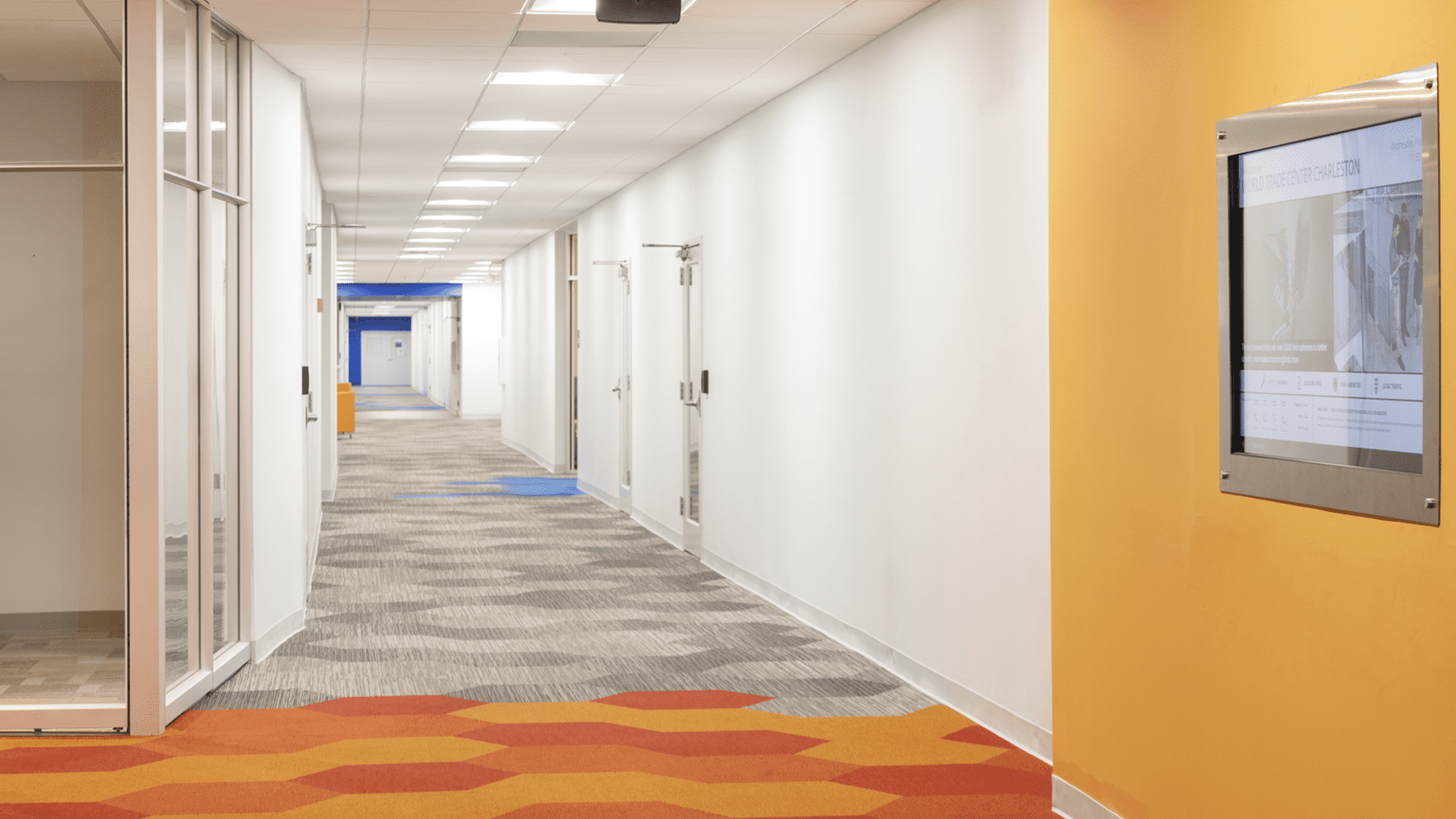 Hallway with white and yellow walls and orange/yellow and brown carpet