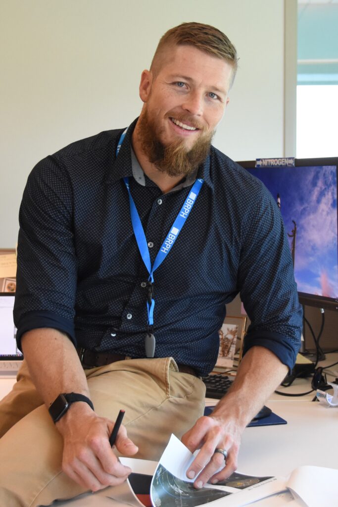 Man sitting on desk smiling at camera