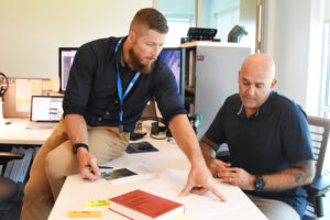 Two men sitting at a desk looking at papers
