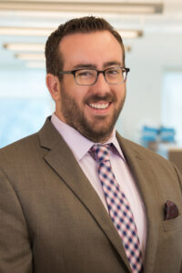 Man in brown jacket with glasses and beard
