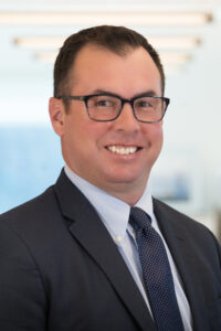 Man in shirt, tie and jacket smiling at camera