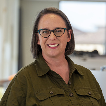 woman in green dress with glasses, smiling