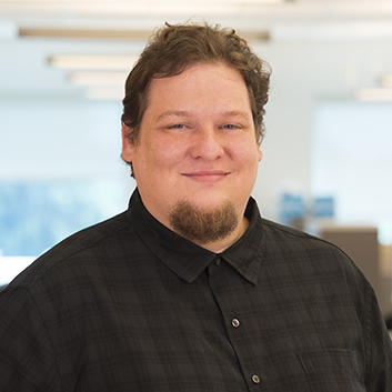 Adam Stadnick Man with goatee and black plaid shirt.
